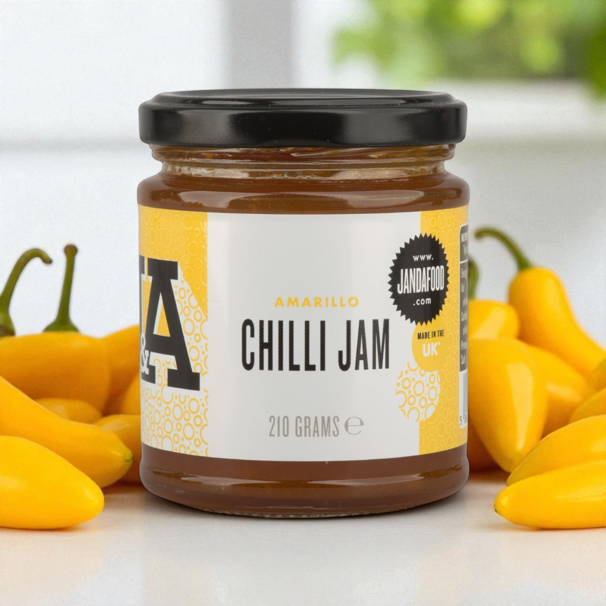 Janda Food Amarillo Yellow Chilli Jam in a glass jar surrounded by fresh yellow Aji Amarillo chillies
