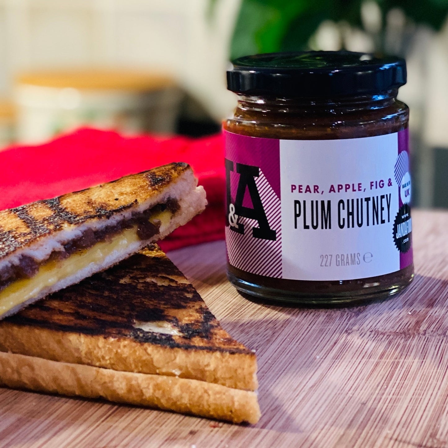 Janda Food pear, apple, fig and plum chutney jar served with a toasted cheese sandwich on a wooden board