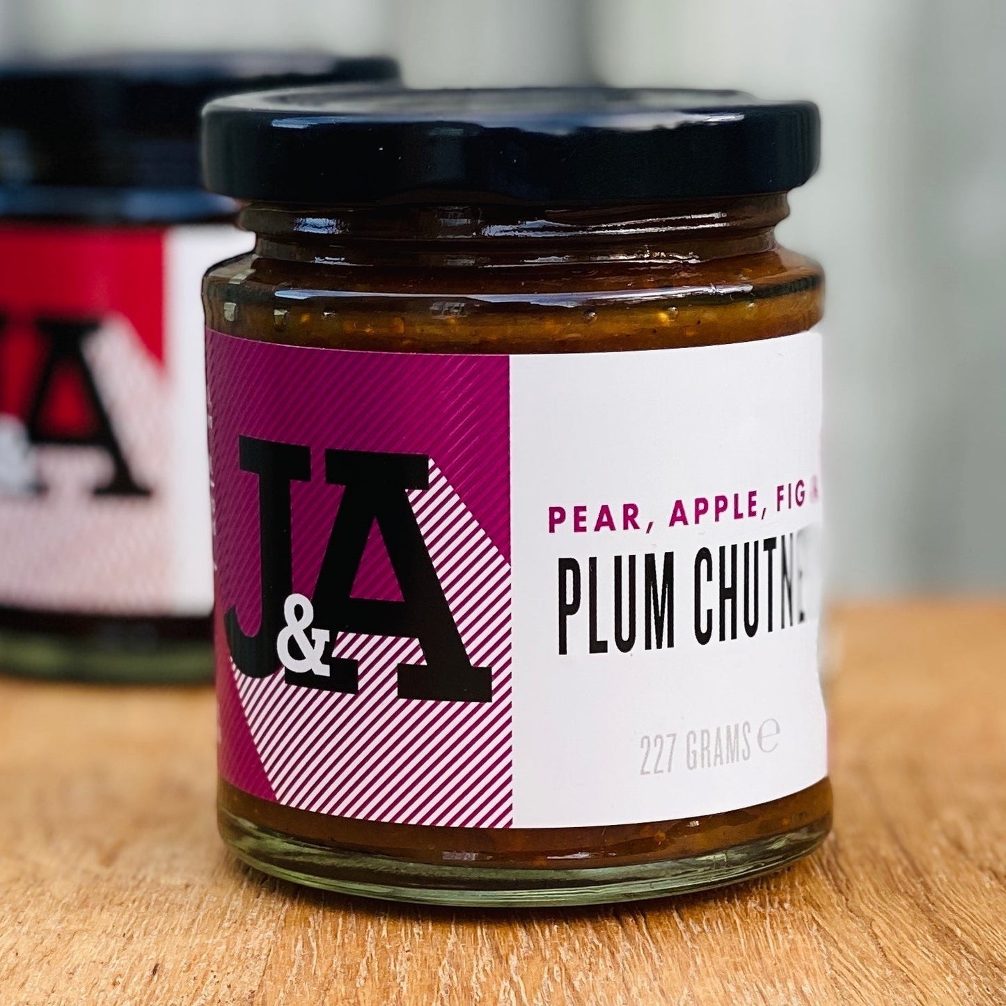 Janda Food plum chutney jar with pear, apple, and fig, featuring a modern purple and white label on a wooden surface.