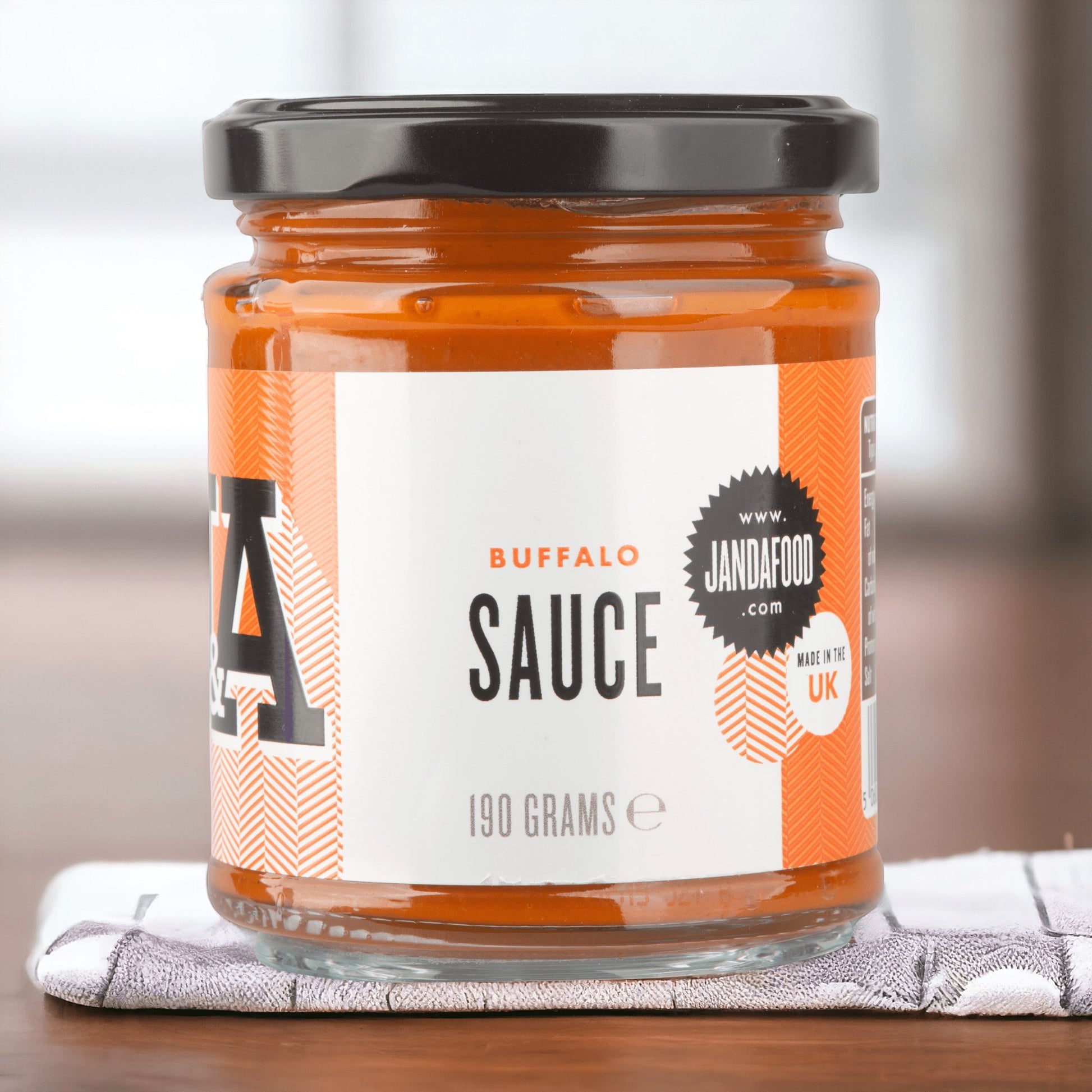 Janda Food vegan buffalo sauce in a glass jar with orange label, crafted with aged jalapenos in the UK.