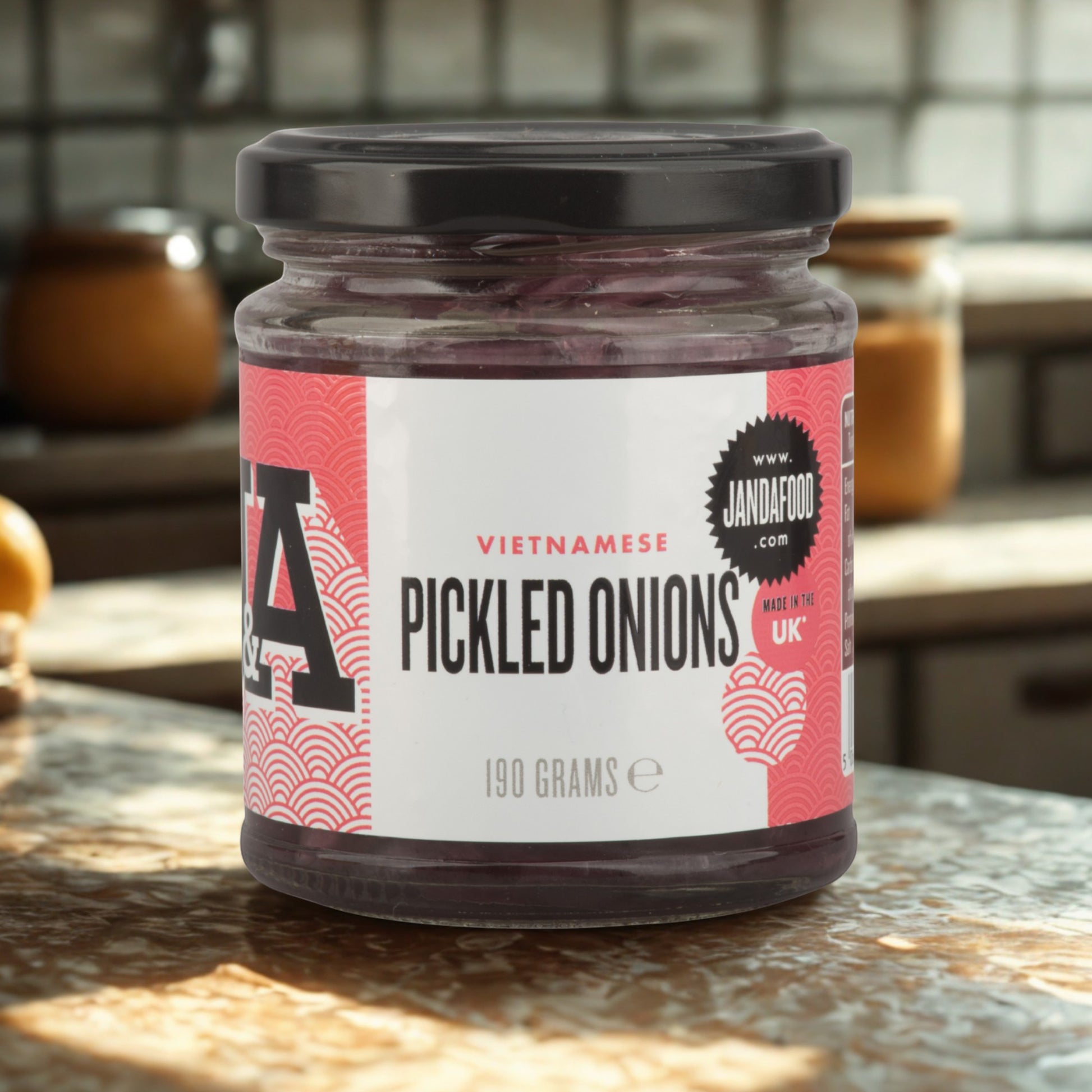 Janda Food Vietnamese pickled red onions in a 190g glass jar with a black lid, sitting on a kitchen countertop.